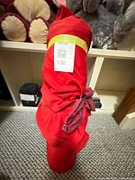 Full view of red fabric bolt standing upright with label and purple tie