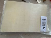 Front view of gesso-primed canvas on wood board with sizing ticket visible