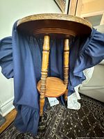 Underside view of oak table with spindle legs and attached blue skirt