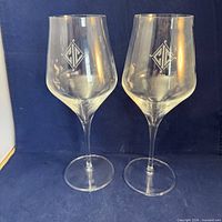 Front view of both wine glasses showing bowl shape and etched monogram logo