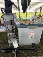 Overall view showing walking boot, Sterilite bin, lace doily and partial cane parts