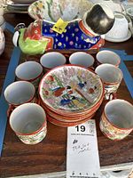 Stack of saucers, surrounding cups, reclining figurine pillow