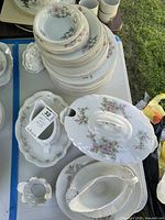 Stacked plates, bowls, serving pieces including oval platter, gravy boat, covered dish