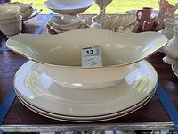 Oblong Lenox bowl atop stack of matching oval platters showing overall set