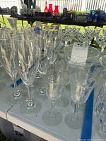 Group of champagne flutes and cordial glasses displaying etched floral pattern and ribbed stems
