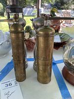 Front view showing both spice mills: tall brass cylindrical mill and shorter nickel-plated mill