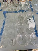 Overhead view of clear glass champagne coupes grouped together with lot tag visible