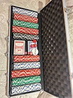 Open aluminum case showing poker chips, cards, dice, dealer button