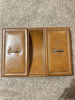 Top view closed showing three leather-covered sections with brass handles
