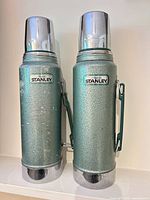 Front view of two matching Stanley Aladdin green thermos bottles