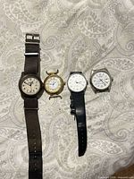 All four watches laid out side by side on fabric background
