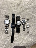 Five wristwatches laid out to show variety and overall condition