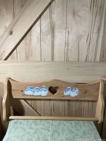 Front view of wooden towel bar showing heart cutout and painted chicks