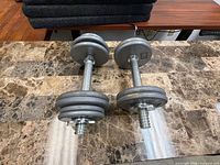Pair of fully assembled adjustable dumbbells on tabletop