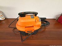 Side view of orange/black Armor All wet/dry vacuum with hose and cord