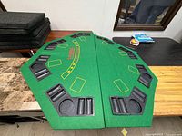 Top view of folded octagonal poker table topper showing felt surface, cup holders and chip trays