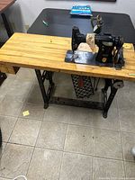 Full view of Singer sewing machine mounted on wood treadle table