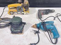 All four corded power tools arranged on table showing overall condition and cords