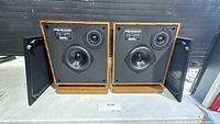Front view of both Design Acoustics PS-10 speakers with grilles removed showing drivers and labels