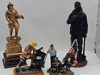 Group view of four firefighter statues/trophies showing overall lot contents
