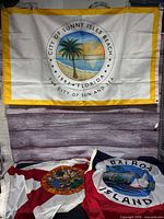 All three flags displayed: Sunny Isles Beach hanging, Florida and Balboa Island flags folded below