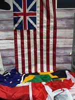 Grand Union flag hanging; Canadian, Jamaican and blue-star flags on floor