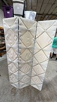 Full view of three-panel ivory tufted room divider standing upright