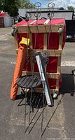 Group shot showing umbrella in sleeve, table, three metal stakes, weed fabric roll