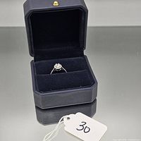 Ring in open presentation box showing halo setting and center stone