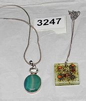 Both necklaces laid out showing chain styles and pendants