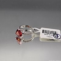 Side profile of sterling silver ring showing red/pink center stone and CZ accents