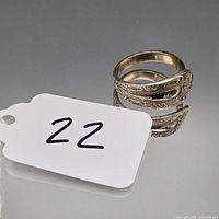 Front view of ornate sterling silver spoon ring beside tag