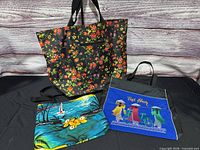 All three tote bags laid out: black floral, blue Jamaica, blue Viet Nam