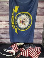 Large U.S. Navy flag, uniform cap, several small U.S. flags