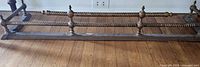 Full length view of brass fireplace fender showing rope rail and supports