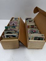 Two long cardboard boxes filled with unsorted trading cards