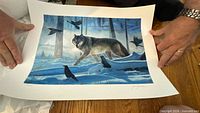 Full view of the unframed print showing wolf scene, margins, hands for scale