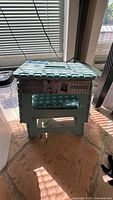Front view of teal plastic folding step stool