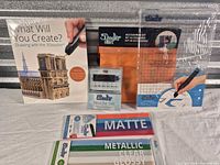 Lot overview showing project book, accessory bag, nozzle set, DoodlePad and two filament packs