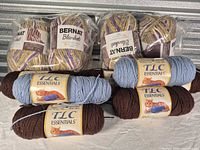 Overall view of eight yarn skeins including sealed Bernat packs and loose TLC Essentials skeins