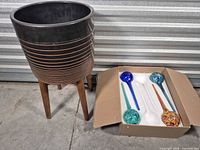 planter on stand beside open box of watering globes