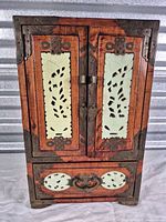 Front view of wood cabinet showing jade insets and brass hardware