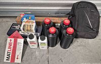 Group view of chemicals, tanks, mat cutter, mat ruler, boxed items and backpack