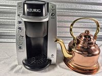 Keurig coffee maker beside copper kettle