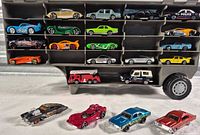 Open case showing interior compartments and vehicles plus four cars displayed in front