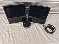 Two Echo Shows, one Echo Dot, power adapter visible
