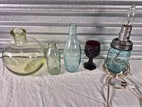 Group shot showing all five glass items: round bottle, Dr Pepper bottle, Pureoxin bottle, ruby goblet, Mason jar lamp