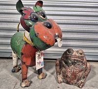 Metal dog sculpture and concrete frog planter side by side