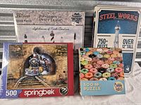 Group shot of four sealed puzzle and model kit boxes