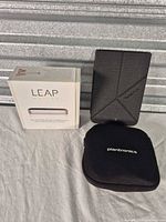 Group shot of Leap Motion boxed, PocketBook e-reader with cover, Plantronics case